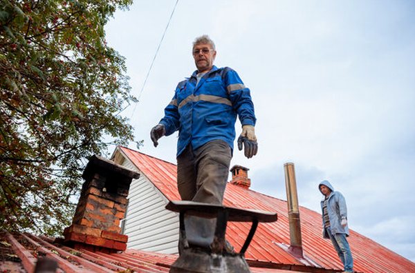 Two crew members reconnoitering a roof between chimneys